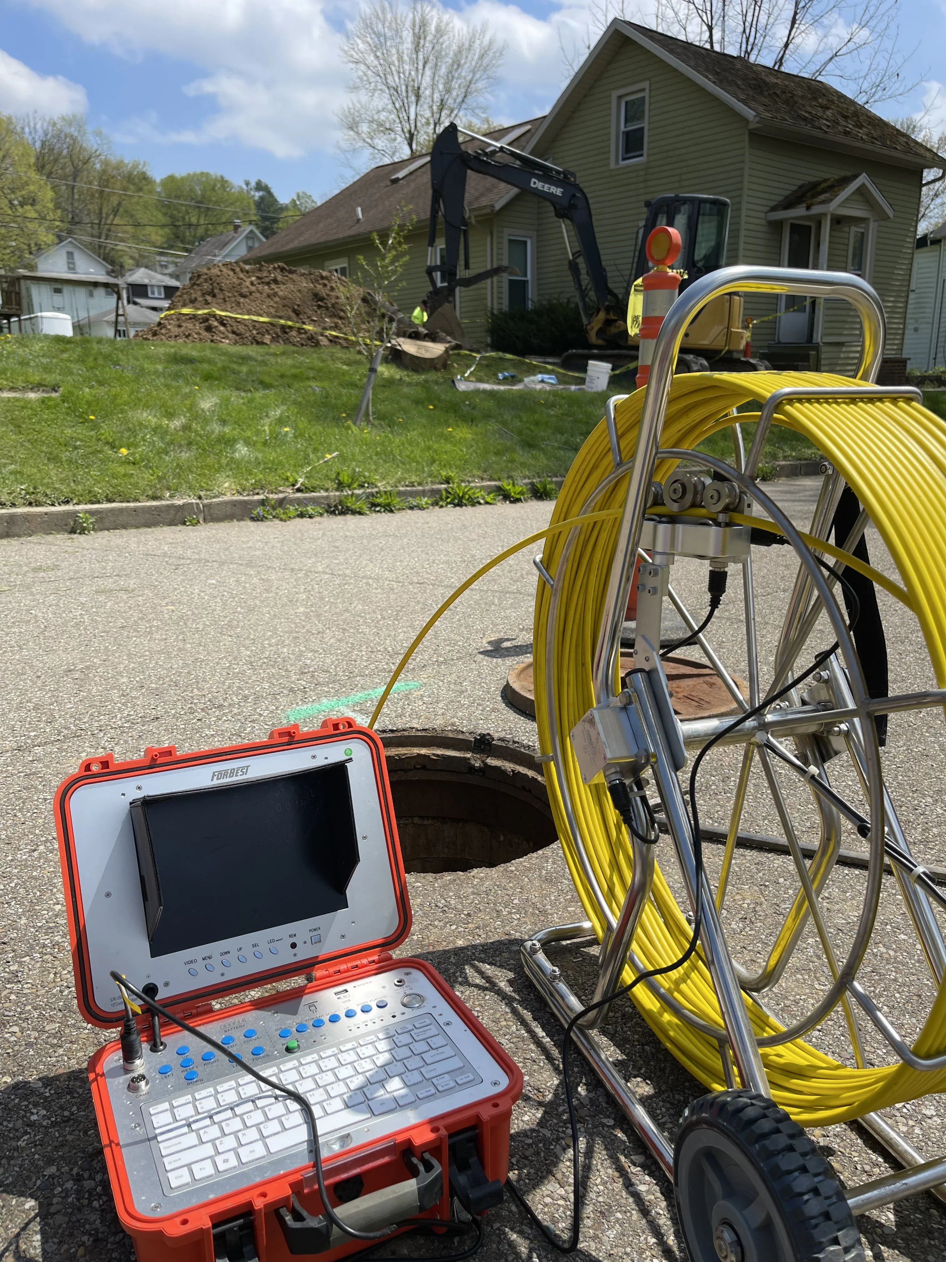 Technician performing sewer line camera inspection with diagnostic equipment