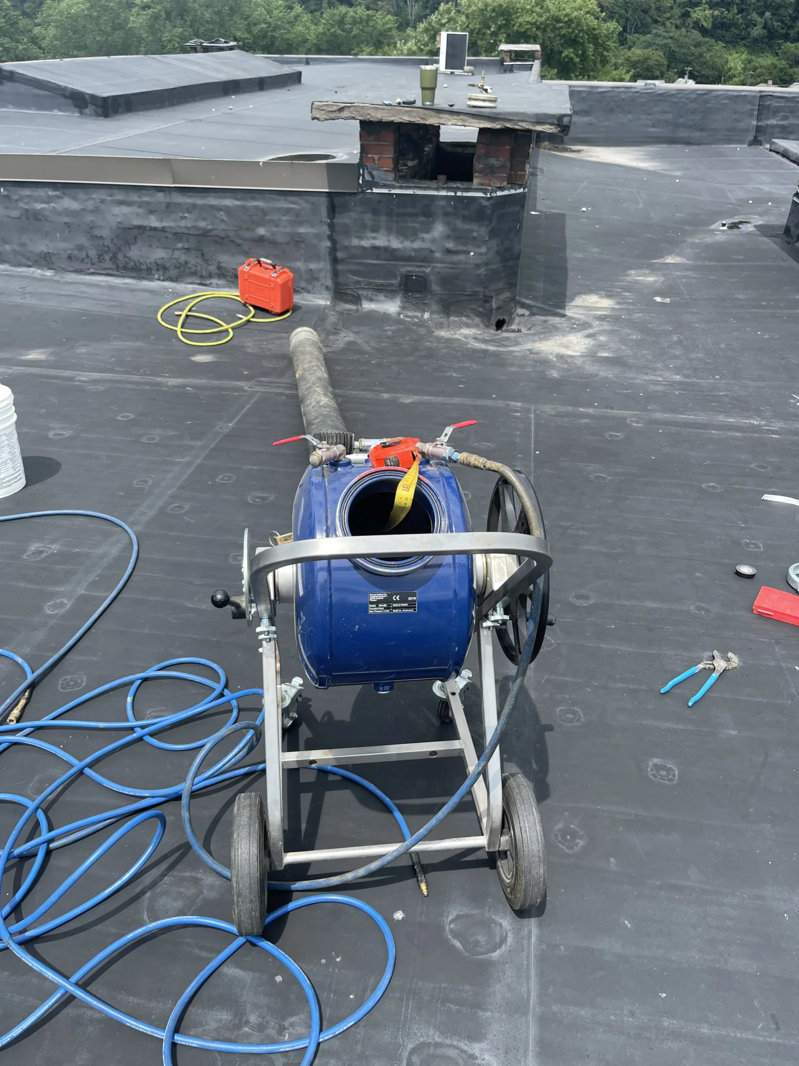 Professional jetting equipment on flat roof with drainage system maintenance in progress
