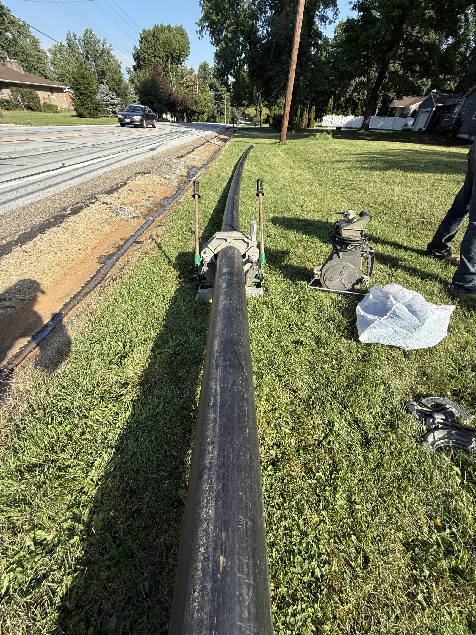 Horizontal directional drilling equipment installing black drainage pipe underground with minimal lawn disruption