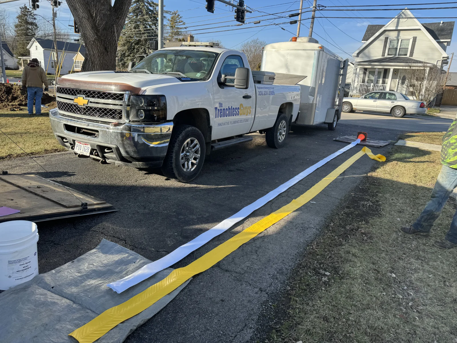 Trenchless drainage installation with blue and yellow barriers on residential driveway