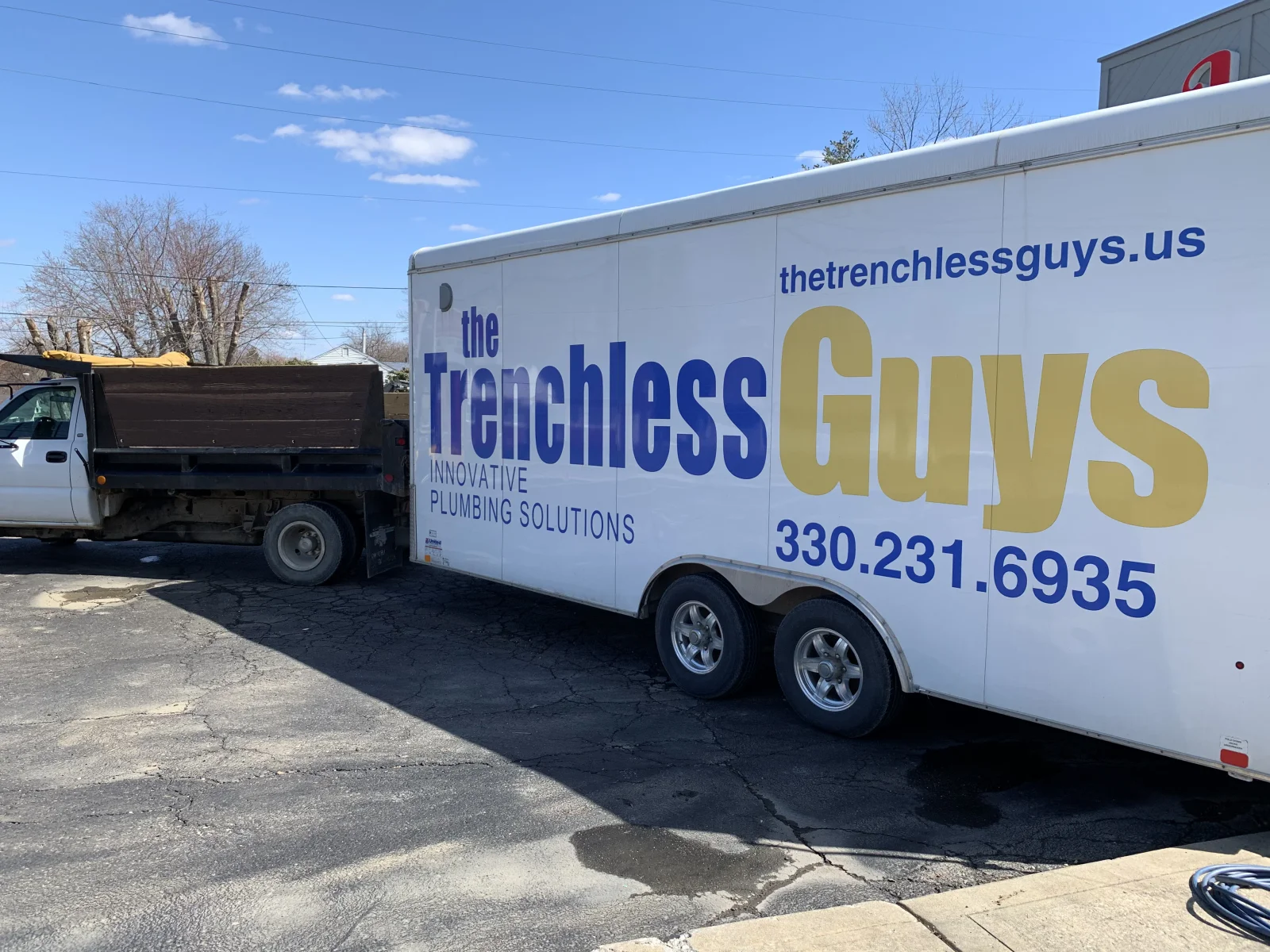 White enclosed trailer with blue and gold vinyl wrap lettering for plumbing service company