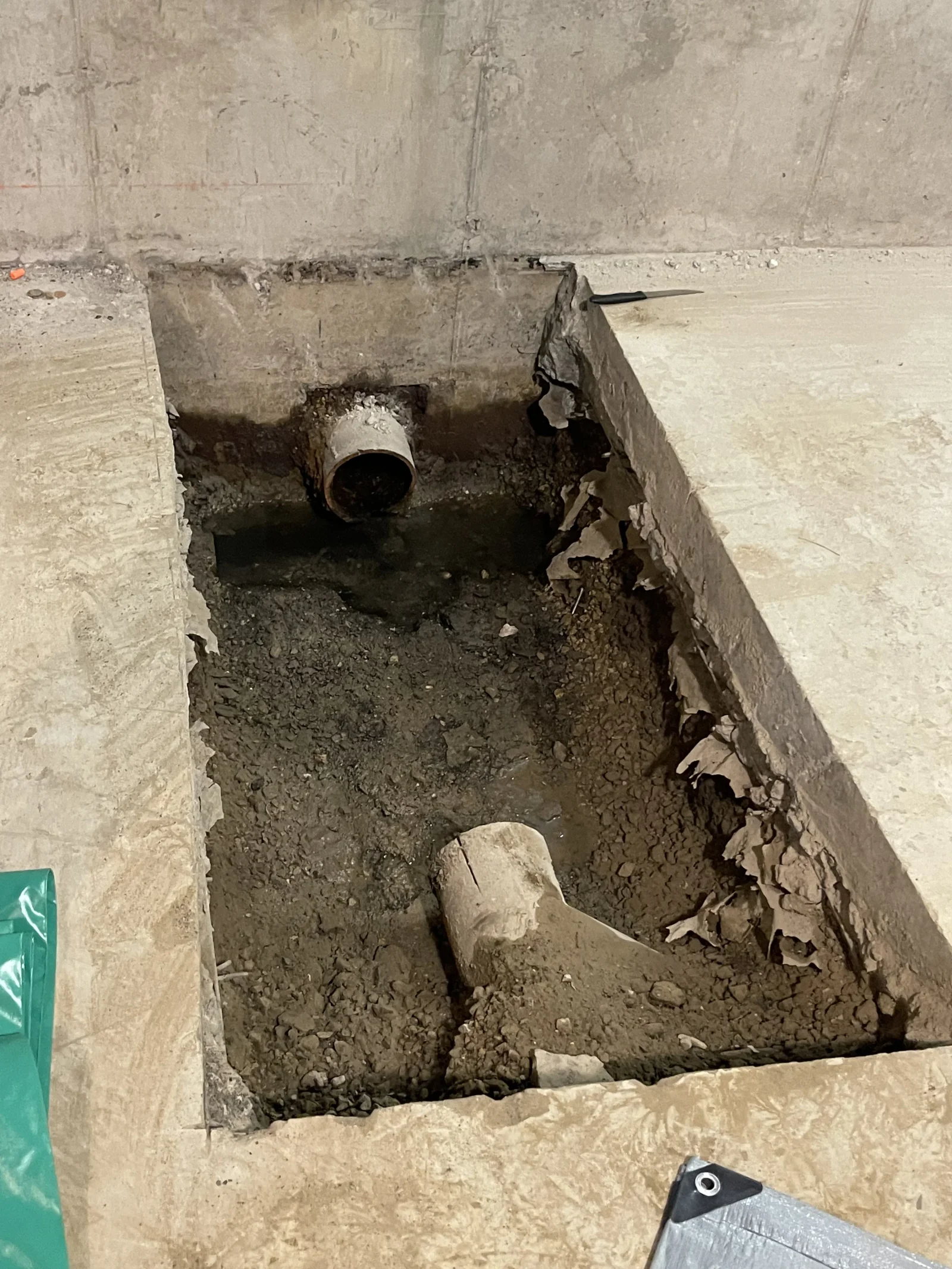 Concrete floor drain installation with PVC pipe and gravel base in excavated trench