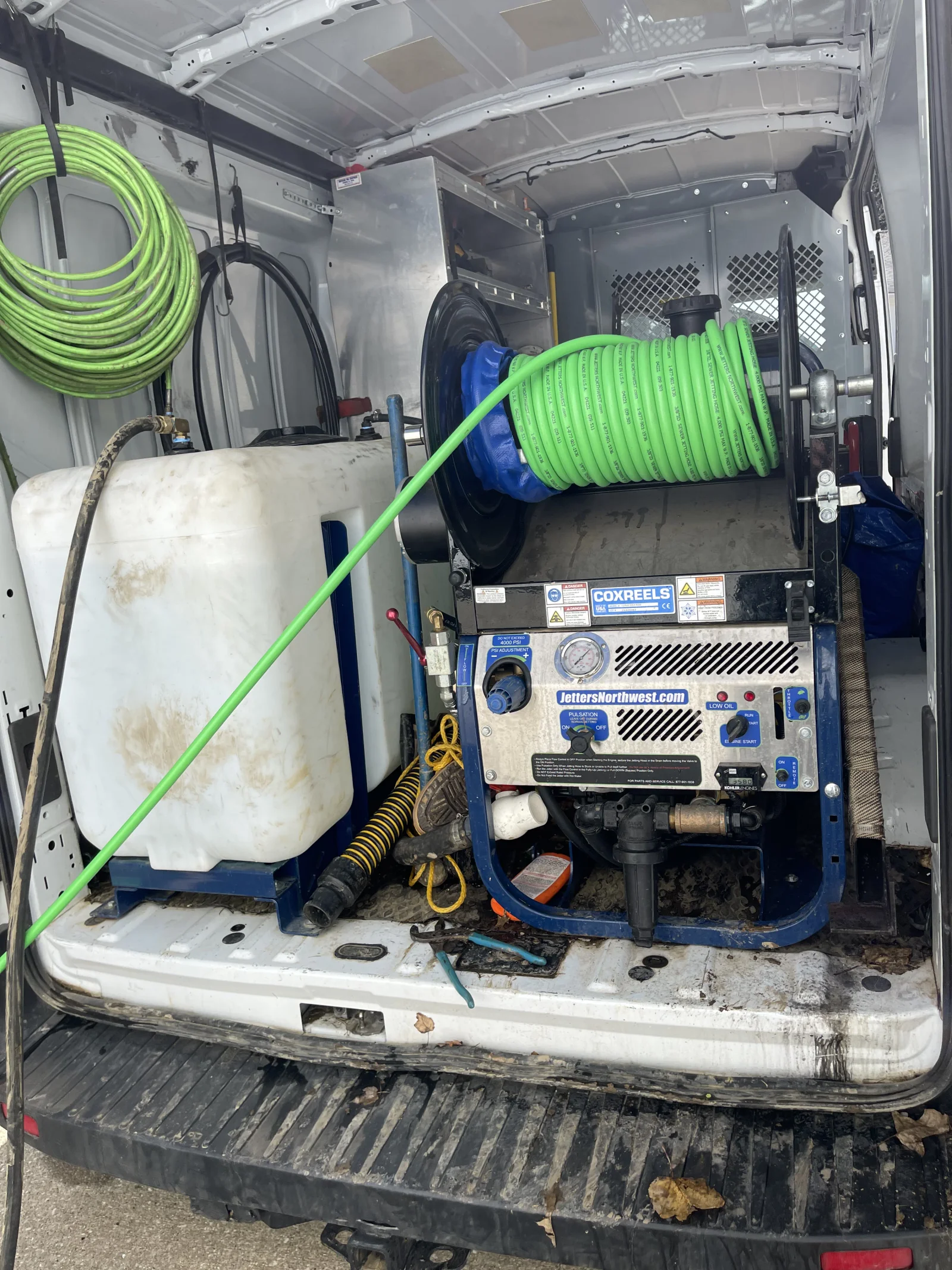 Service van interior with pressure jetting equipment, hose reels, water tank, and drain cleaning tools