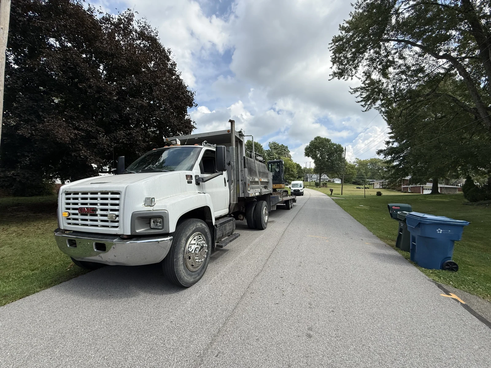 White GMC dump truck with enclosed box on residential driveway for drainage service