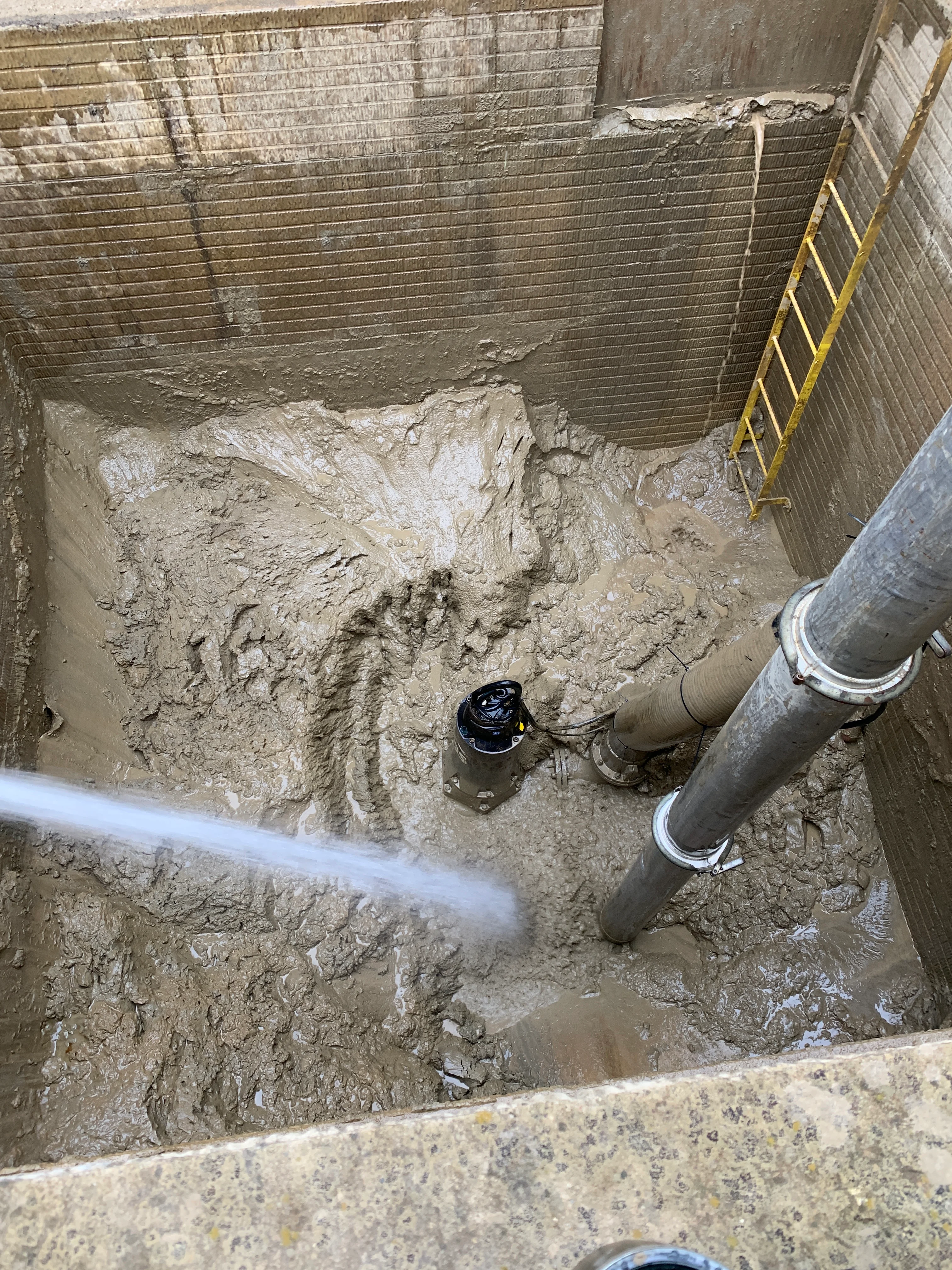 Sump pump installed in concrete pit with gray discharge pipes and sealed connections